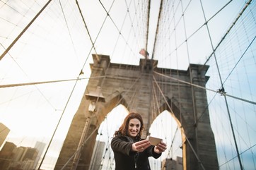 Young woman taking self portrait on Brooklyn bridge, New York, USA