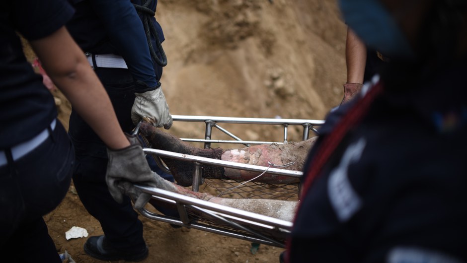 Firemen carry a body recovered from under the debris in the village of El Cambray II, in Santa Catarina Pinula municipality, some 15 km east of Guatemala City, on October 3, 2015 after a landslide late Thursday struck the village. At least 32 people were killed and about 600 others missing following a landslide that damaged some 125 homes on the outskirts of the Guatemalan capital, an official said Friday, noting that the death toll could rise as rescue efforts continue. AFP PHOTO / JOHAN ORDONEZ (Photo credit should read JOHAN ORDONEZ/AFP/Getty Images)